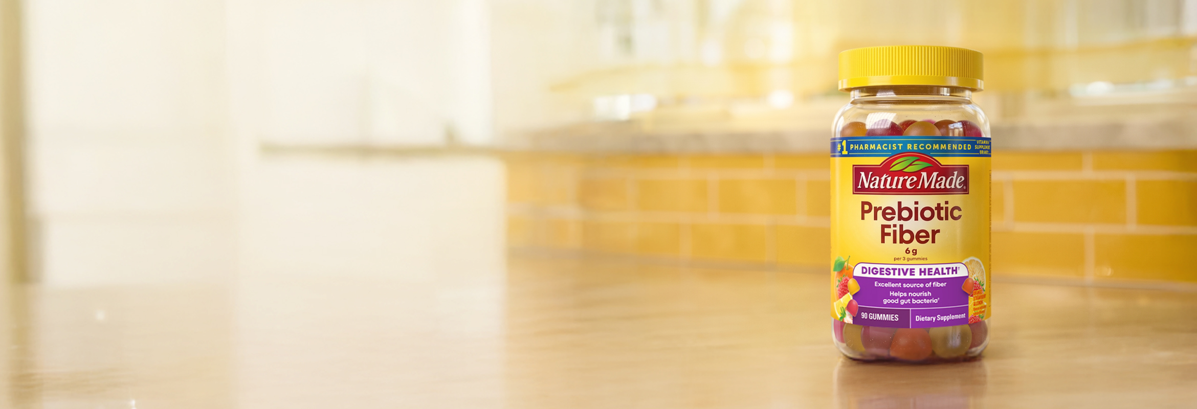 Nature Made Prebiotic Fiber gummies on a kitchen counter with a yellow tile background.