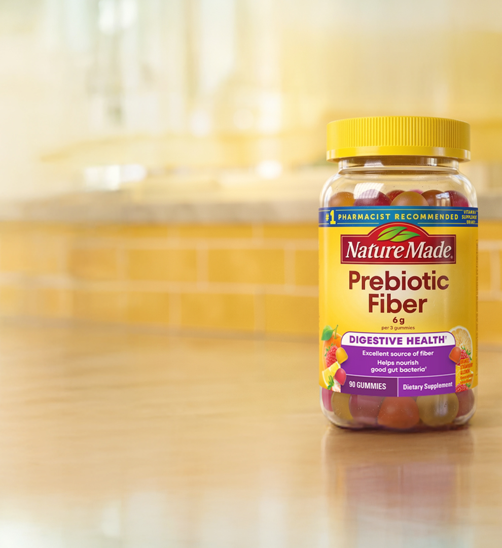 Nature Made Prebiotic Fiber gummies on a kitchen counter with a yellow tile background.