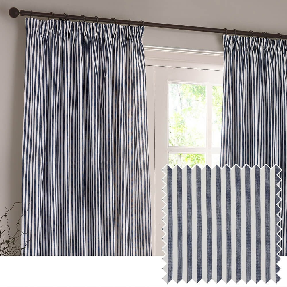 A set of cotton pencil pleat curtains with a navy and white design of vertical stripes, hung on a black curtain pole in front of a neutral wall.