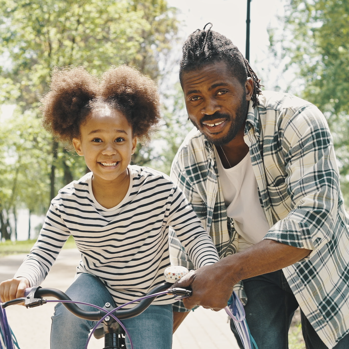 Active family of father teaching his daughter how to ride a bicycle. 