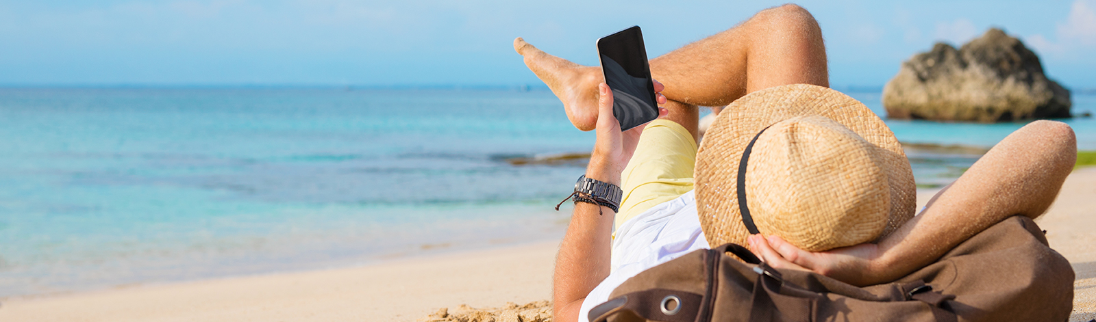 Guy with smartphone lying on the beach