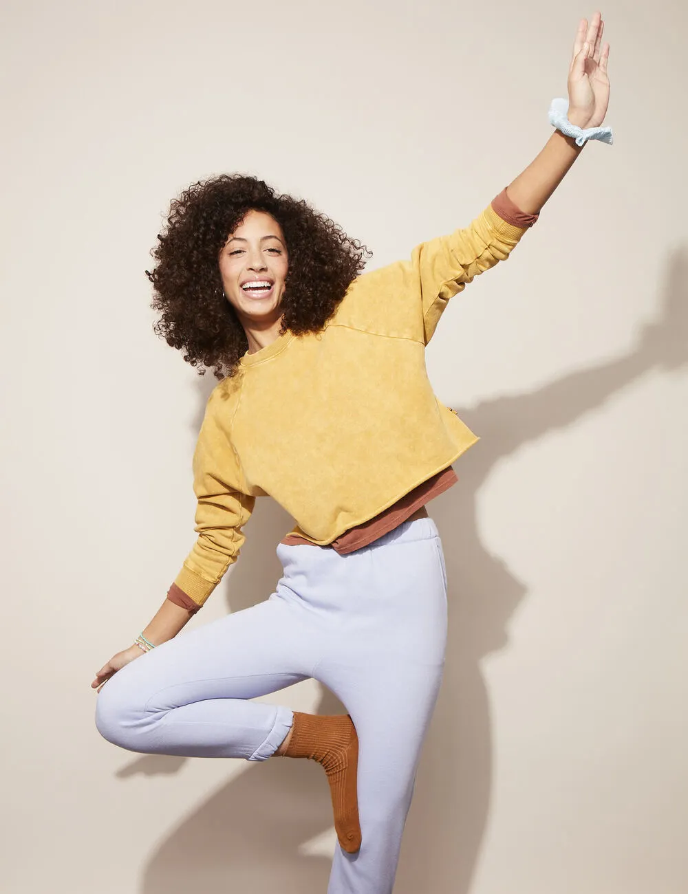 Woman in sweats balances on one leg. 