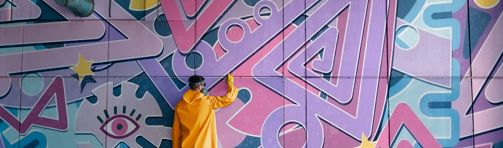 Street artist painting colorful graffiti on wall