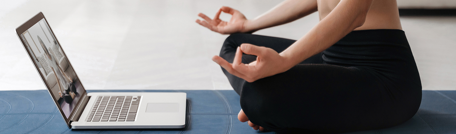 Woman sitting cross legged while doing virtual yoga