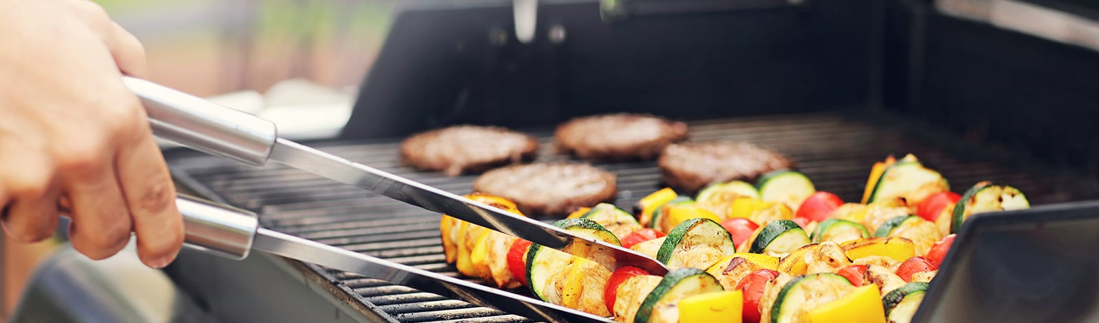 Vegetable skewers and burgers on the grill