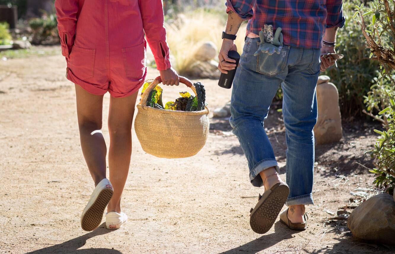 Lady carrying picnic basket and man carrying Sonos Roam 