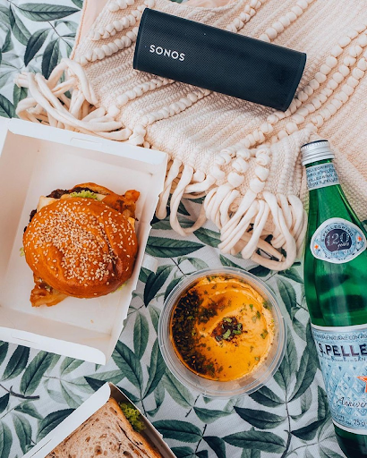 Sonos Roam on picnic mat next to food and drinks