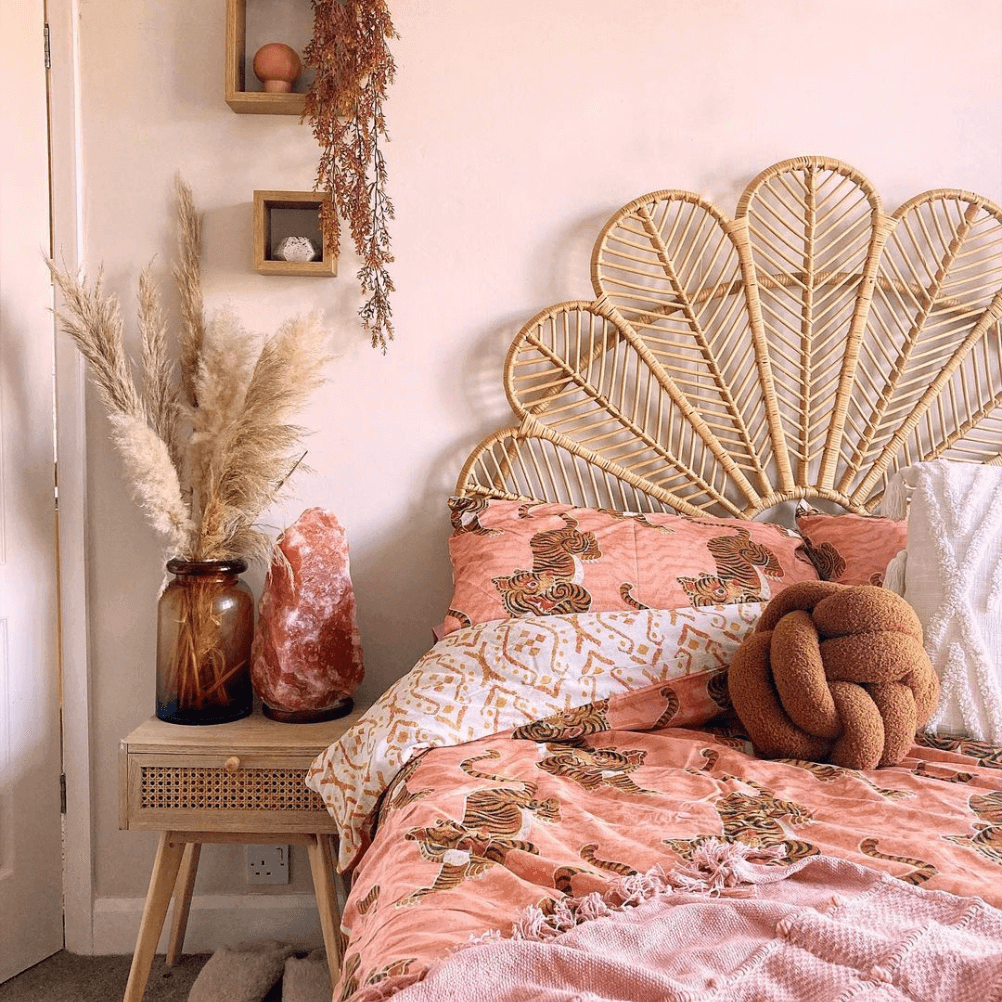 a pink bedroom with a peacock style rattan headboard and coral tiger print bedding.
