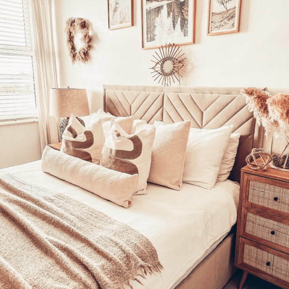 a very stylish, neutral bedroom with cream bedding, lots of cushions and a throw. 