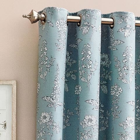 A baby blue curtain panel with an embroidered floral design, hung on a silver curtain pole in front of a neutral background.