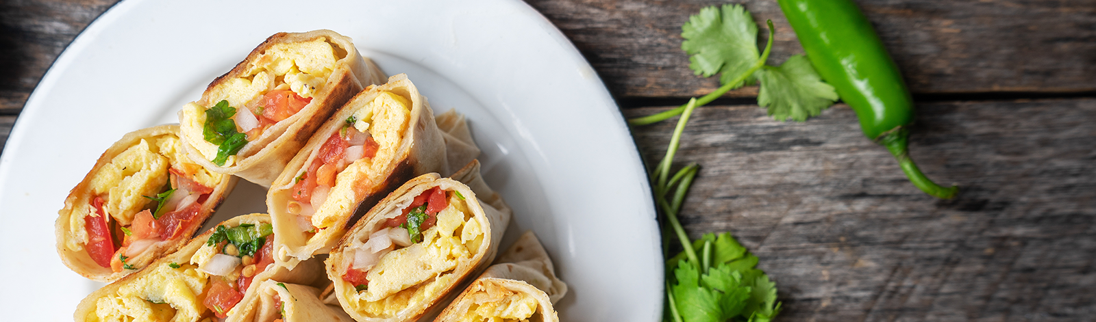 A plate of breakfast burritos on wooden background