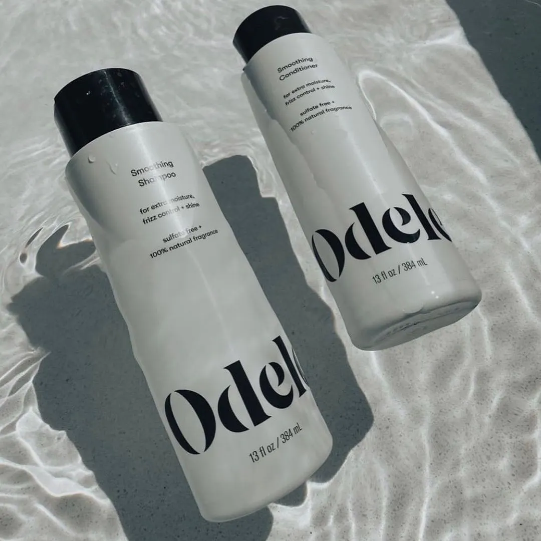 Odele Smoothing Shampoo and Conditioner floating in water under the sun