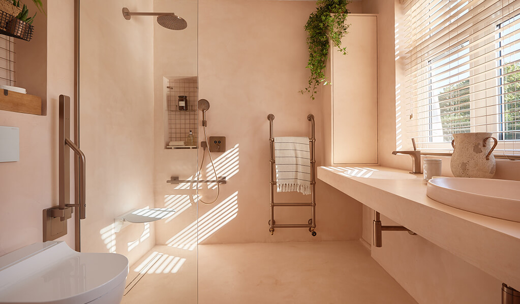 Ade and Lindas Blush pink home bathroom, showing the whole bathroom, flooring and walls are the same tone of blush pink with a rose gold Doc M pack.  
