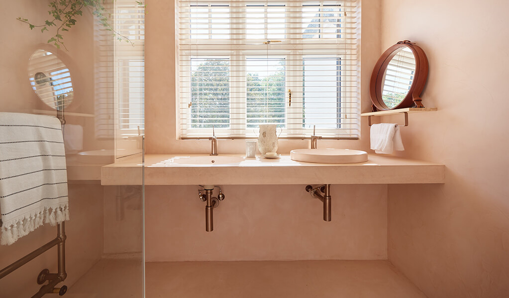 Ade and Lindas Blush pink home bathroom, showing two basins at different heights with a gorgeous big window looking out. 
