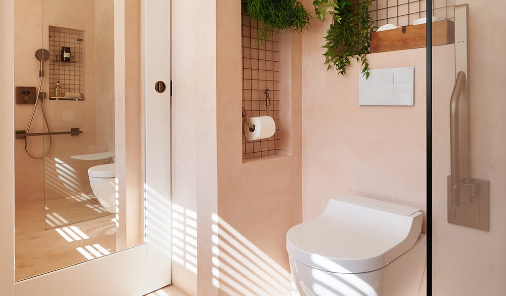 Ade and Linda's blush pink home bathroom, focusing on the large rectangle toilet mirror which is displayed behind the entrance door. 
