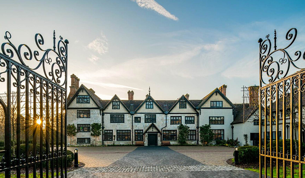 Audley, Stanbridge Earls exterior with a large number of windows sat on a large piece of land. 