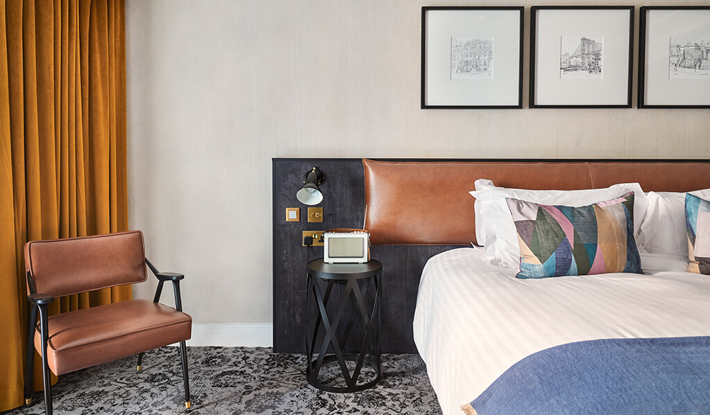 Hotel Brooklyn accessible bedroom including bedside control panel featuring brass switches and sockets. 
