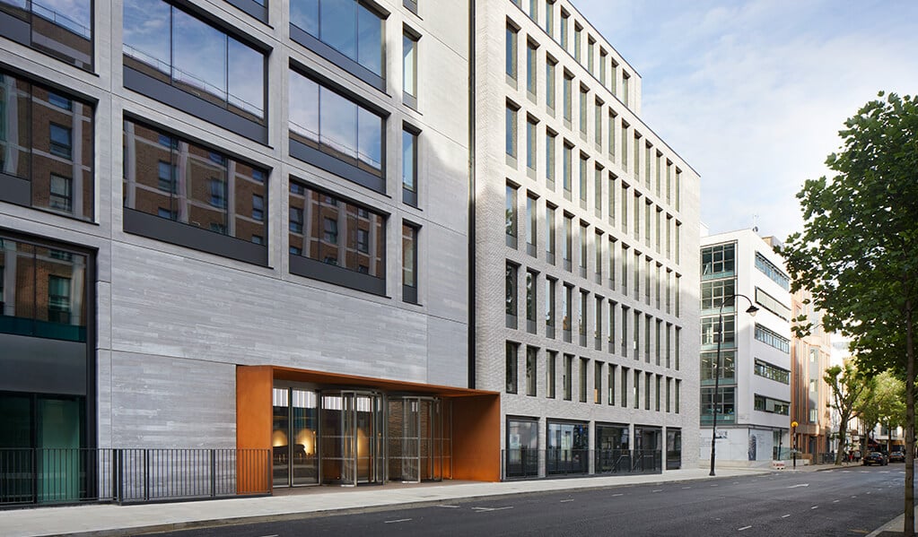 Exterior and street view of 80 Charlotte street. Grey brick building with copper entranceway.