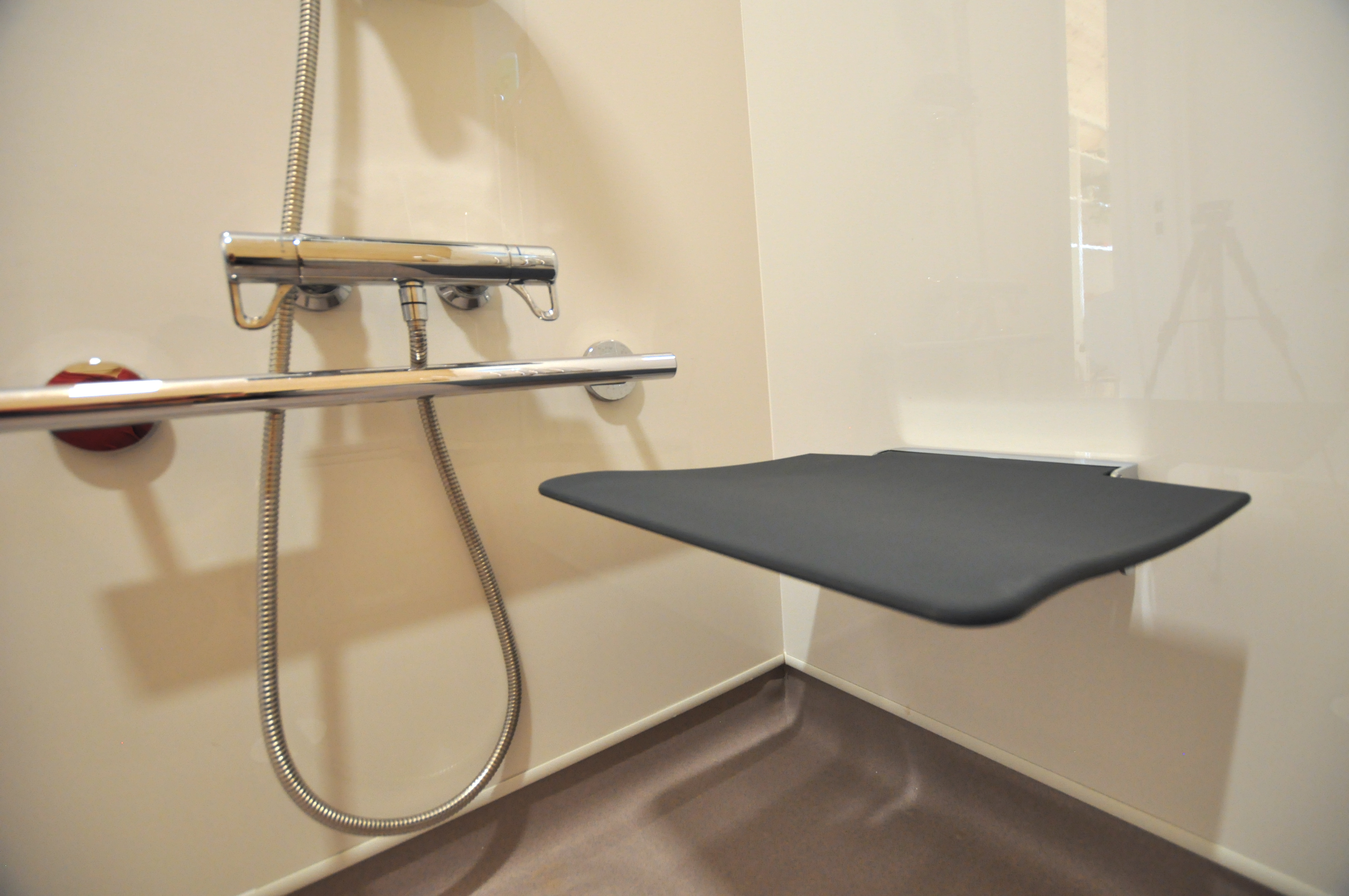 Accessible OmniPod bathroom featuring wall-mounted shower seat and grab rails.
