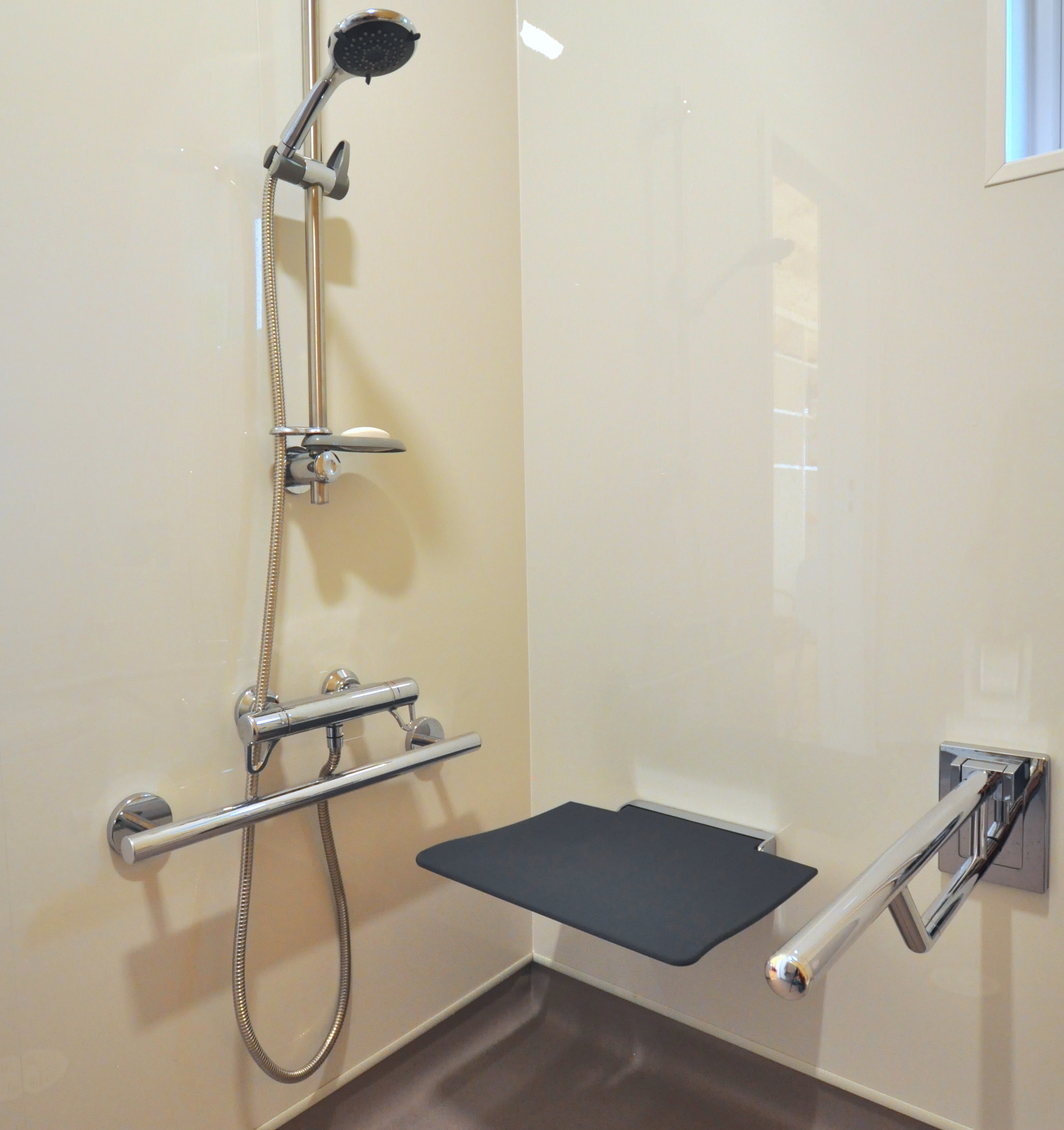 Accessible OmniPod shower area featuring shower seat and grab rails.
