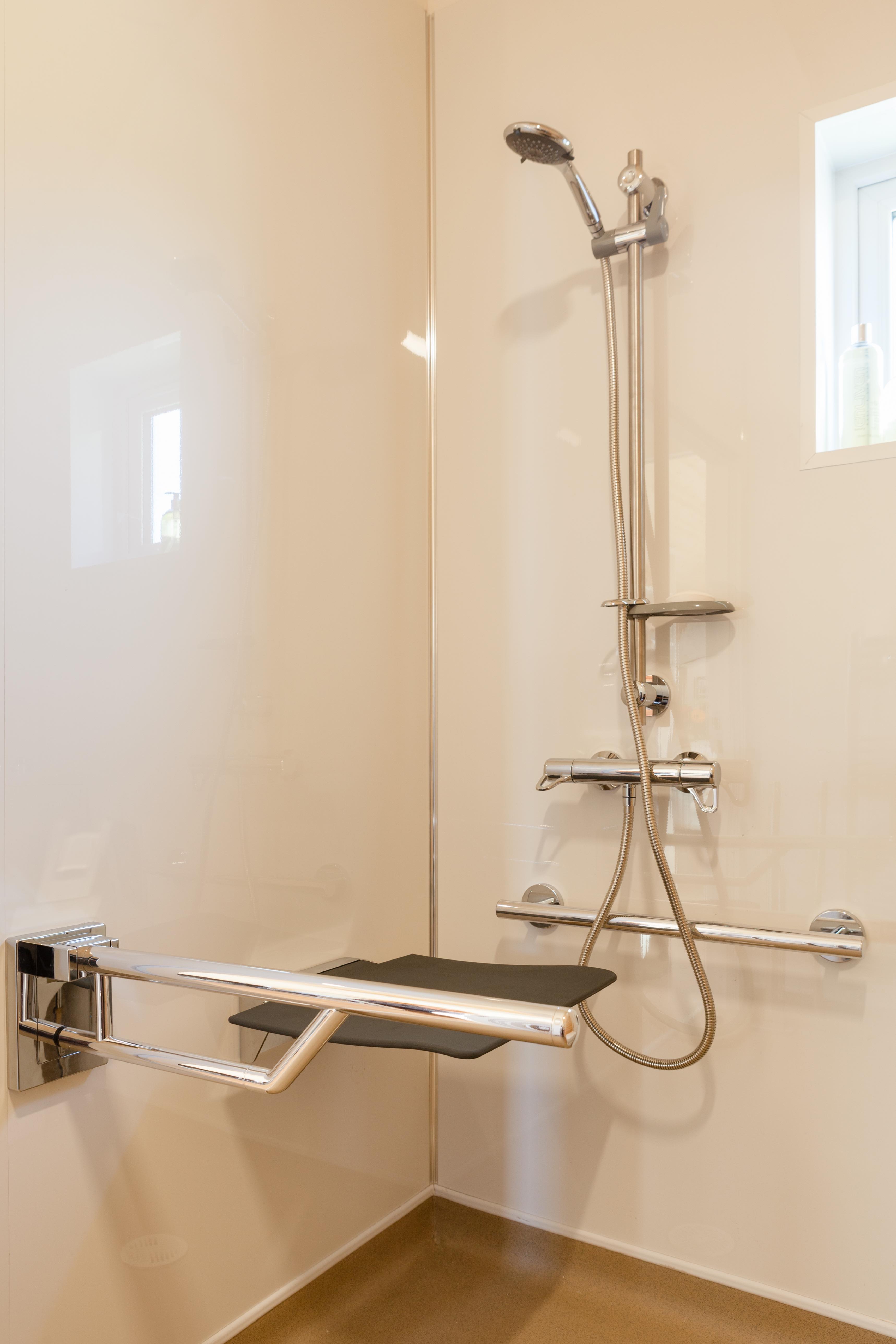 Accessible OmniPod shower area featuring shower seat and grab rails.