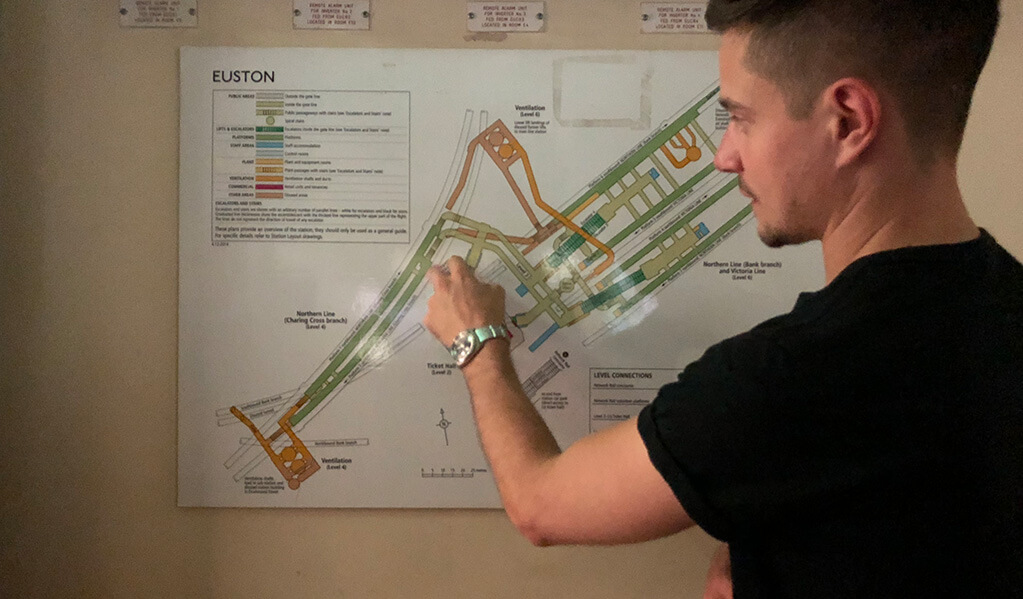 A member of the MotionSpot team looking and pointing at a map of Euston. 
