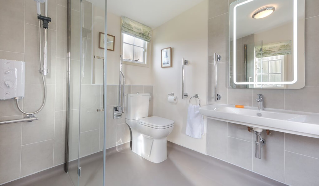 Neutral tone bathroom with chrome detailing throughout, illuminated rectangle mirror above large white basin.

