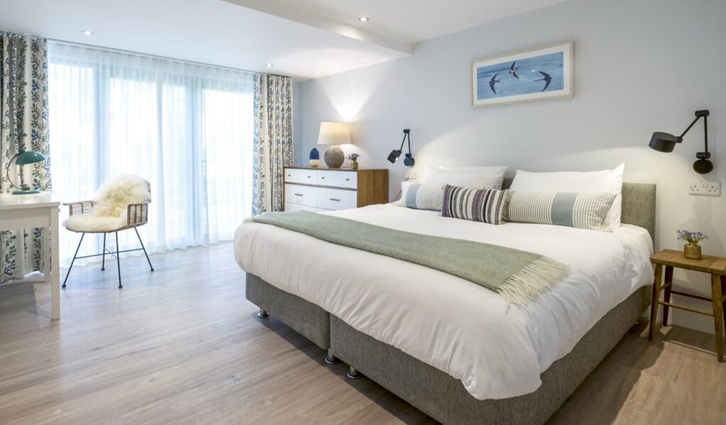 Sail loft bedroom, two single zip together beds with soft coloured finishes, floor to ceiling windows and lovely light grey brown wood floor.  
