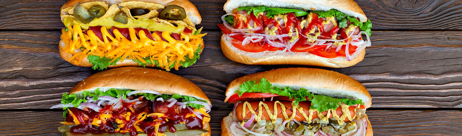 Various hot dogs on a wooden background