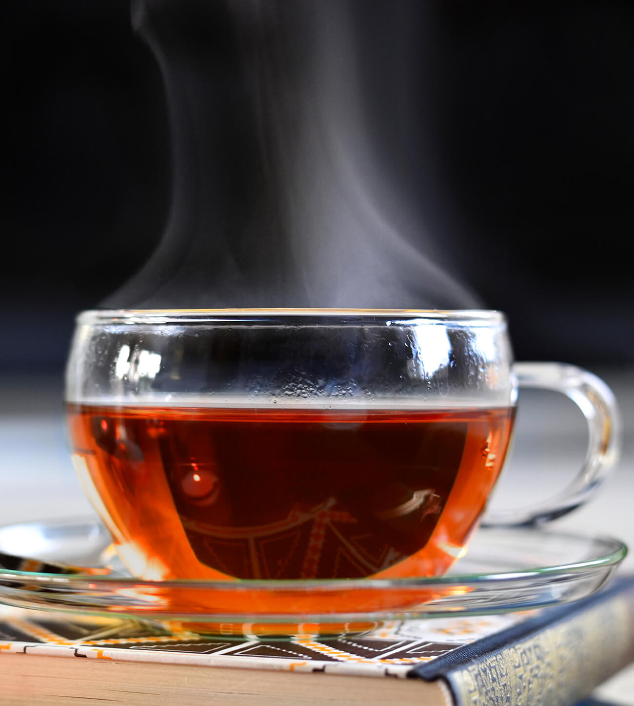 Steaming cup of black tea in a glass cup