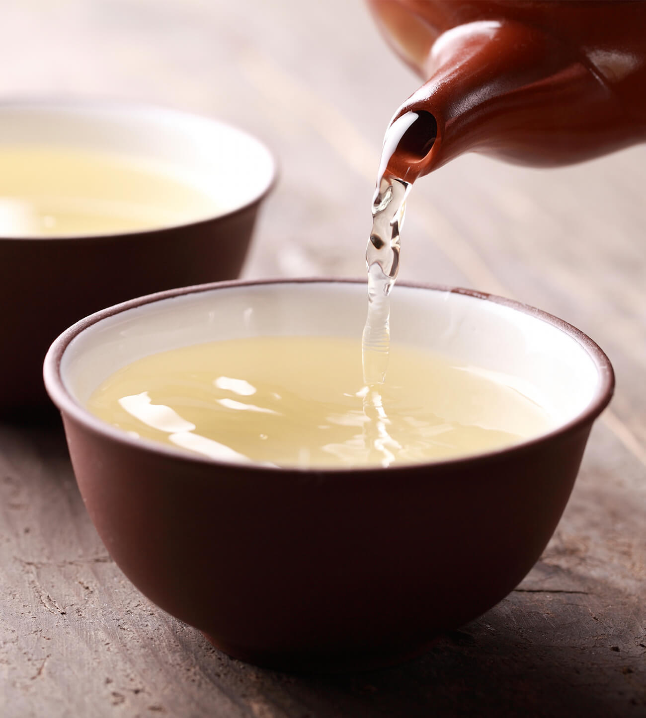 Pouring green tea into a small teacup