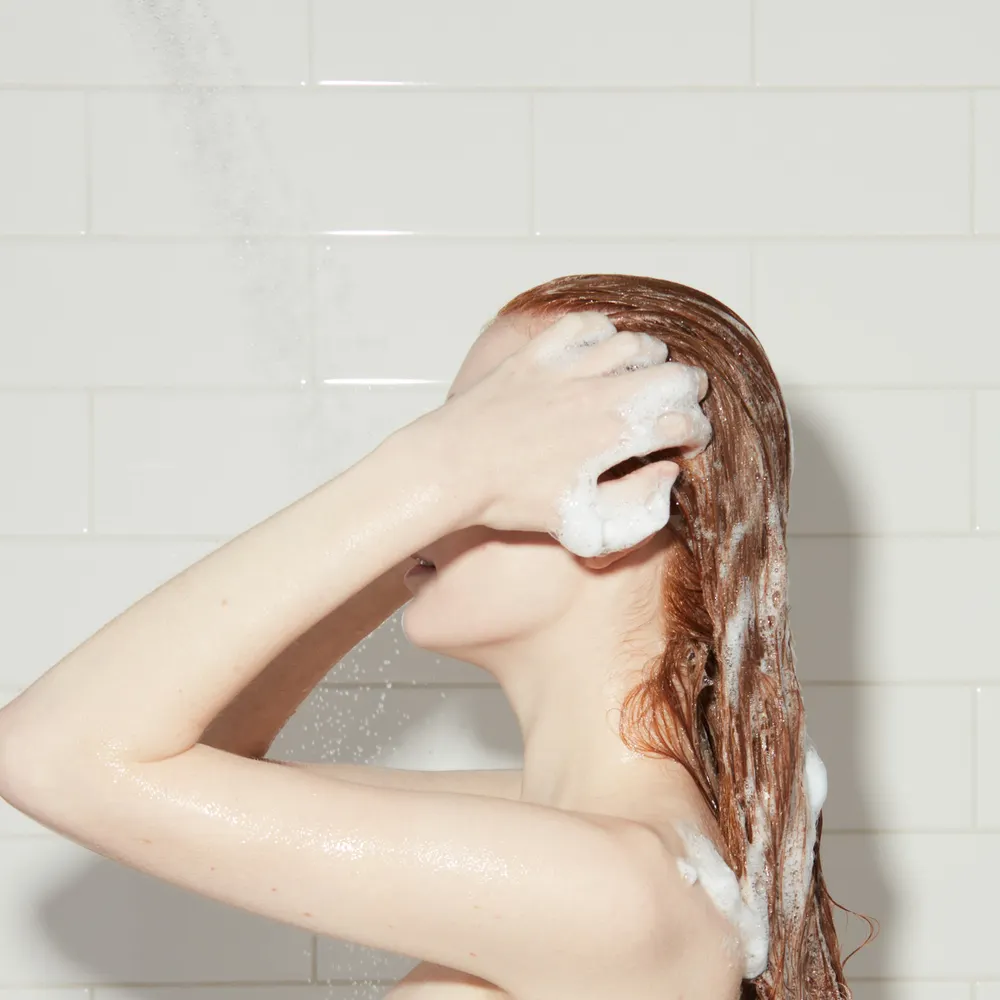 Woman washes her hair in the shower