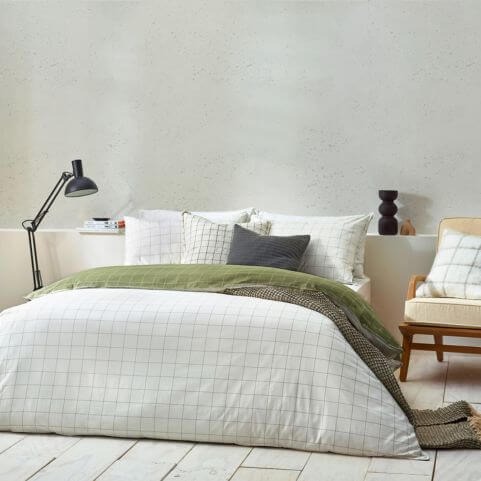 A white 100% cotton duvet set with a contemporary check design, presented on a bed in a neutral white bedroom decorated with coordinating furniture and decor.