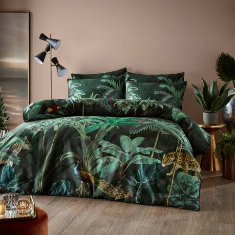 A forest green and black 100% cotton duvet cover set with an exotic design of jungle trees and animals, presented in an earthy neutral bedroom with coordinating decor and indoor plants. 