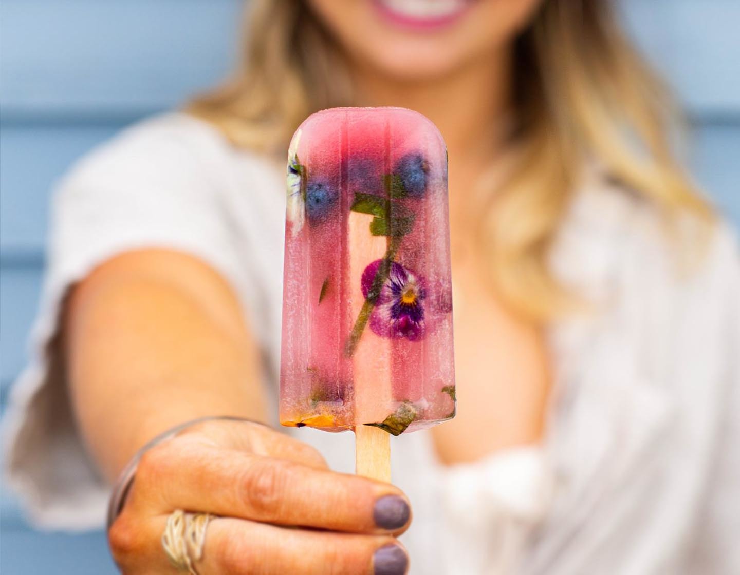 Holding a pink tea popsicle outside