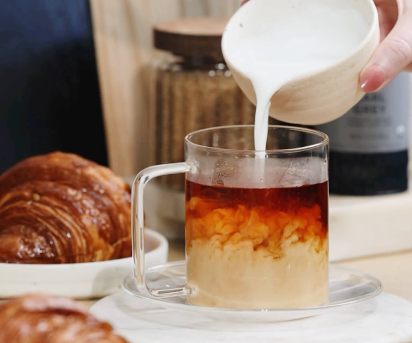 Pouring milk into tea to make a London Fog Latte