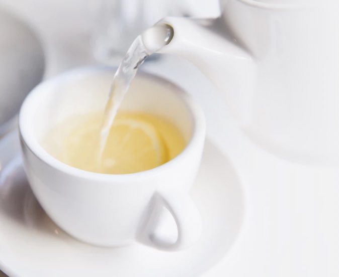 Pouring white tea into a white cup