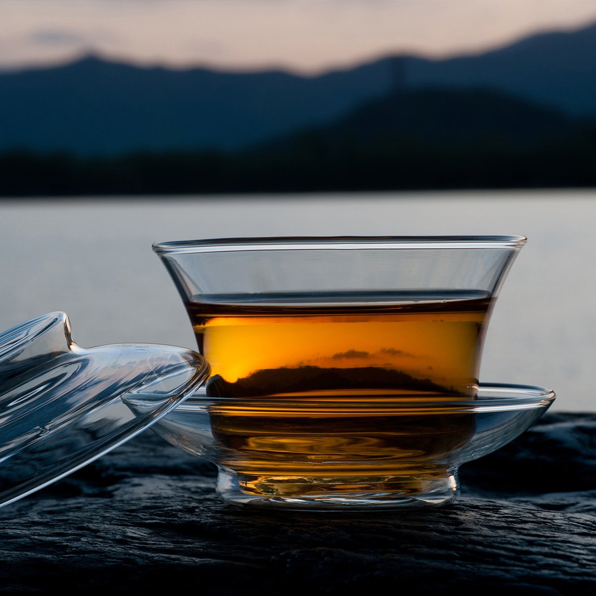 Black tea in a glass cup by a lake in the morning