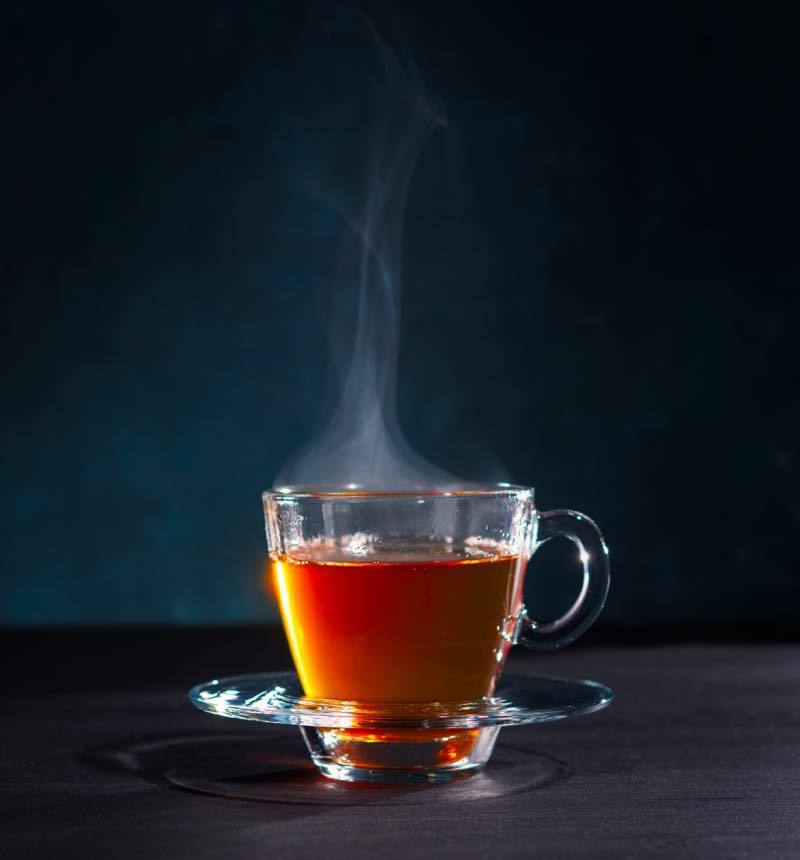 Steaming glass cup of black tea