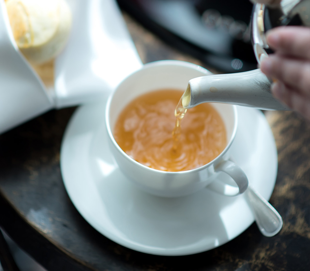 Pouring tea into a white teacup