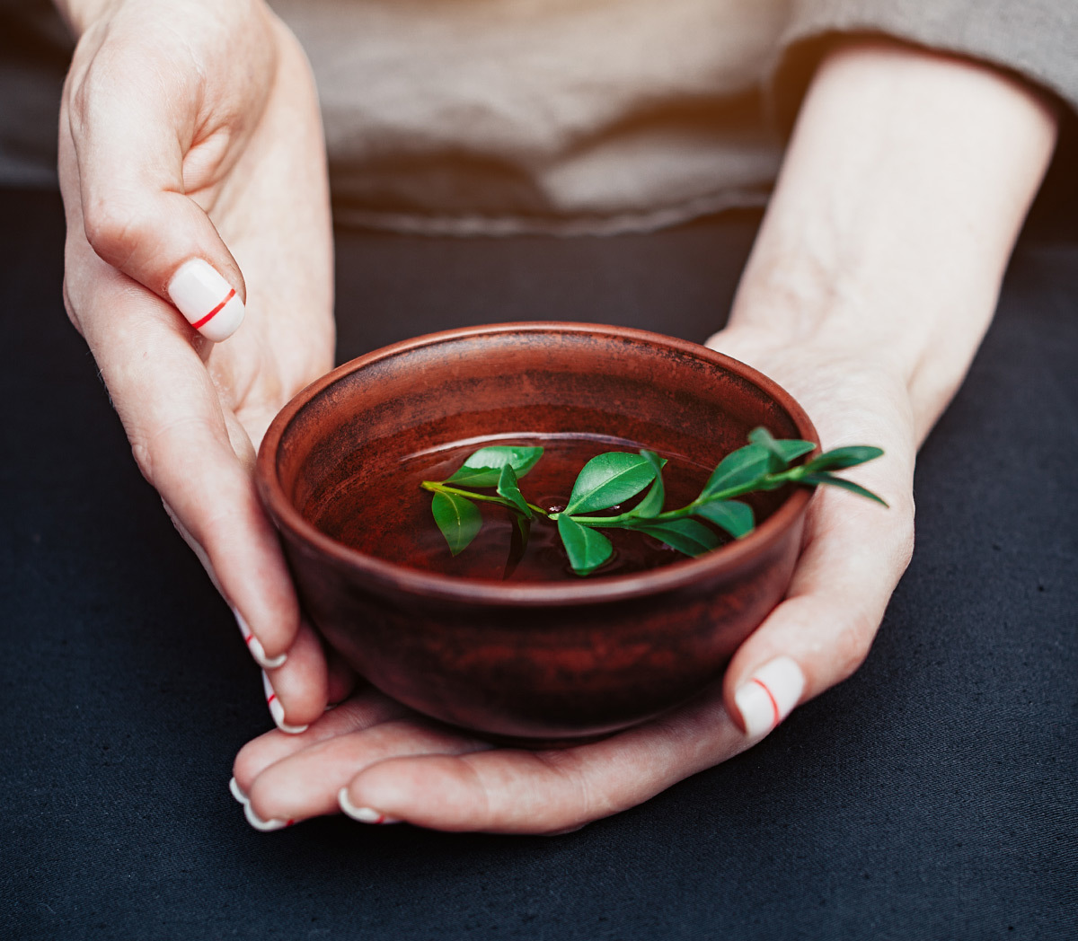 Holding a bowl of tea with fresh tea leaves inside