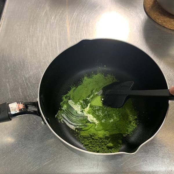 Adding the cream to the matcha powder in small amounts 