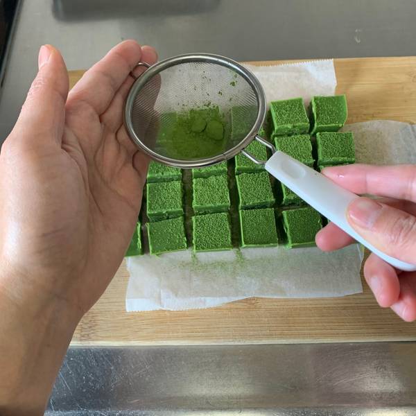 Sprinkling matcha powder over the top