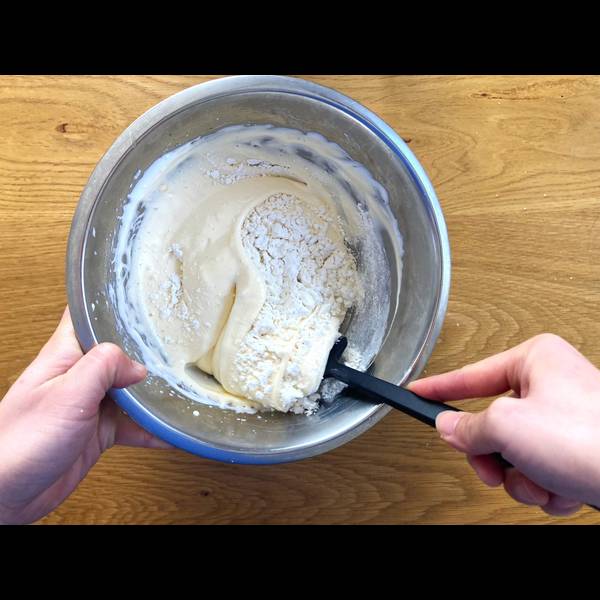 Using a rubber spatula to add in the flour