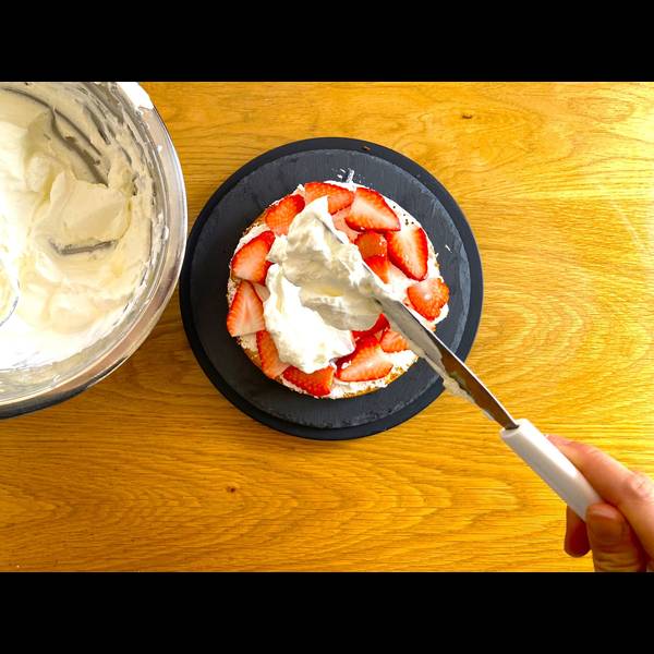 Adding a second layer of whipped cream over the strawberries