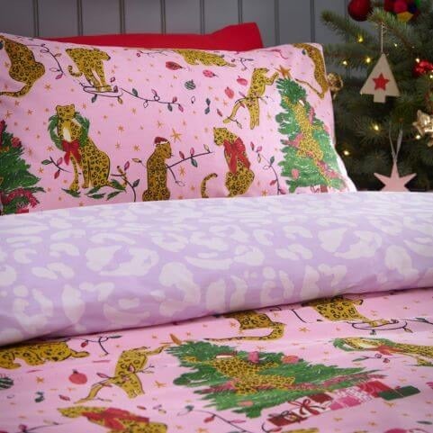 A pink Christmas duvet cover set with a printed design of leopards in festive scenes, complete with a tonal leopard print reverse.