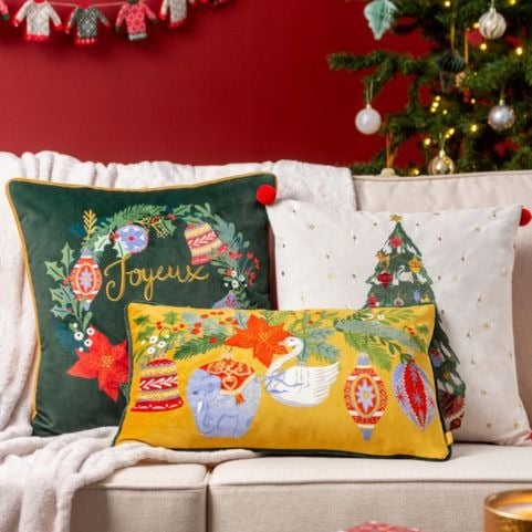 Three traditional Christmas cushions in green, white and gold shades with designs of classic festive symbols.