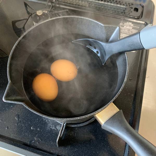 Gently adding the eggs to the pot