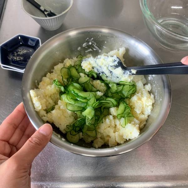 Adding in the sliced cucumbers to the potato salad