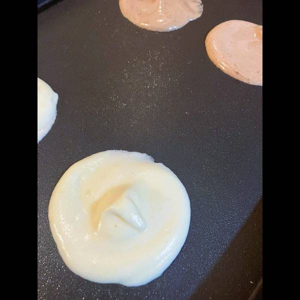 Adding the pancake batter to the griddle in a circular shape